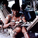 Waiwai woman sitting in a hammock while weaving a seed apron by jellyfish in Hammocks